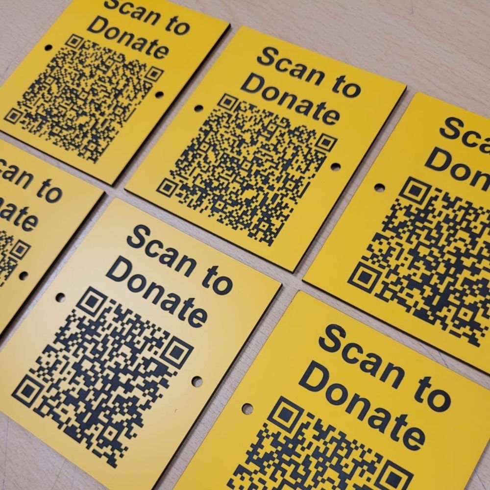 Close-up of a yellow plastic QR label connecting to an online donation and crowdfunding page.